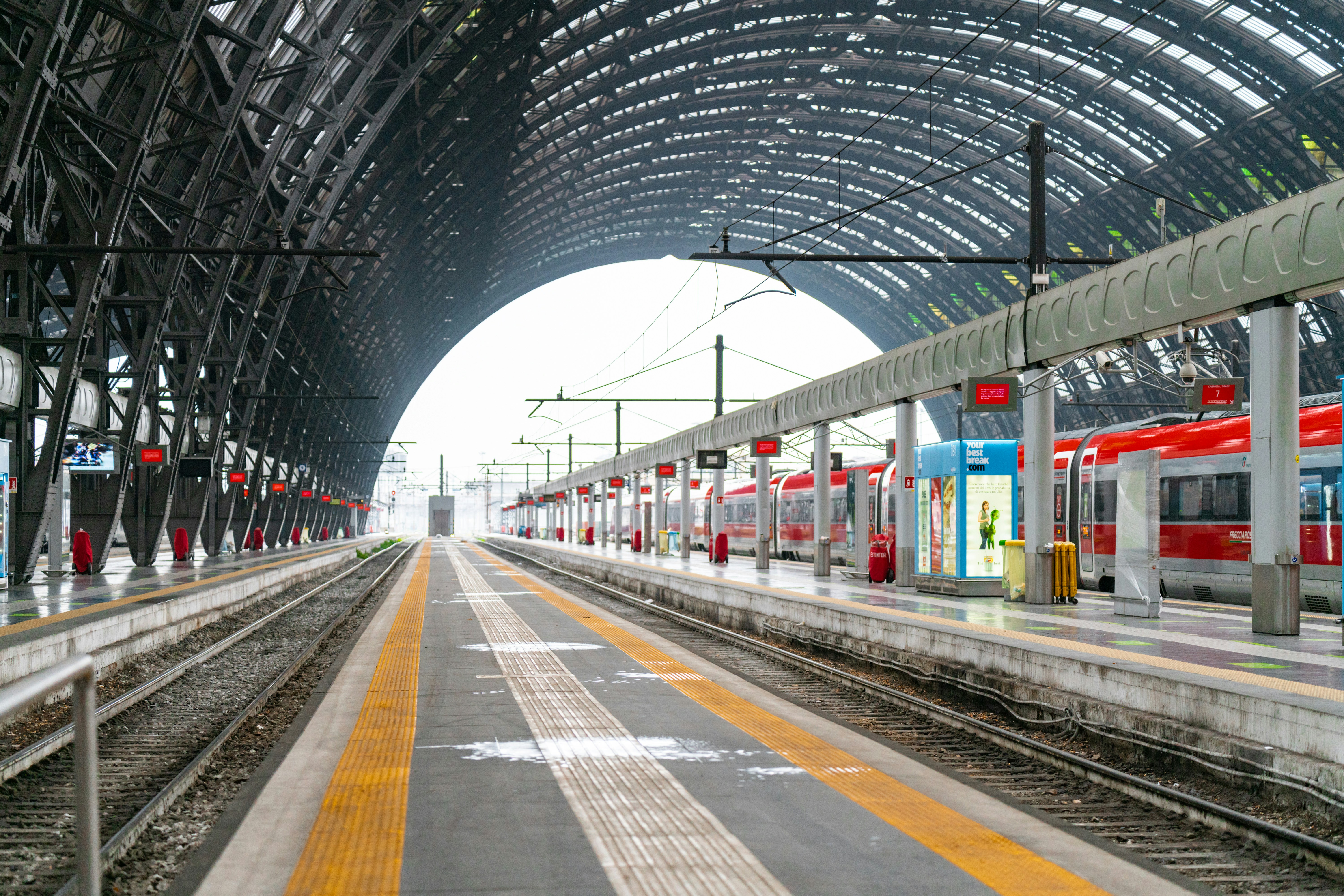 a train station with a train on the tracks, Empty platform of Milano Centrale train station