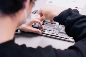 a woman is working on a laptop with her hands