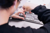a woman is working on a laptop with her hands