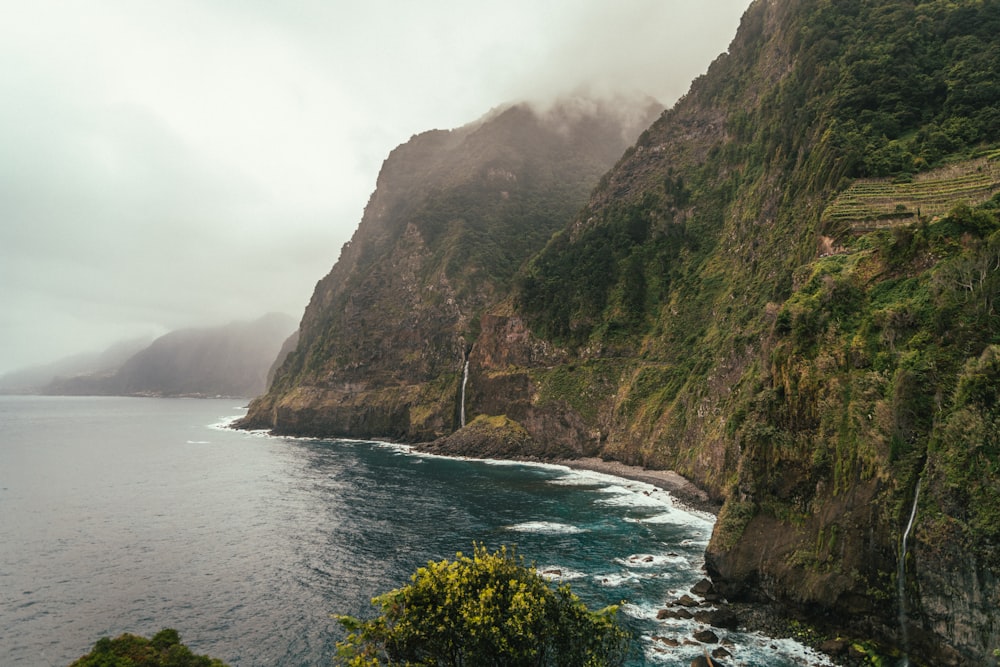 a large body of water next to a lush green hillside