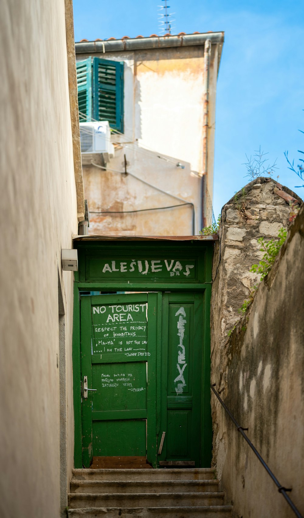 an alleyway with a green door and stairs