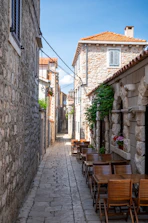 a narrow street with tables and chairs on the side