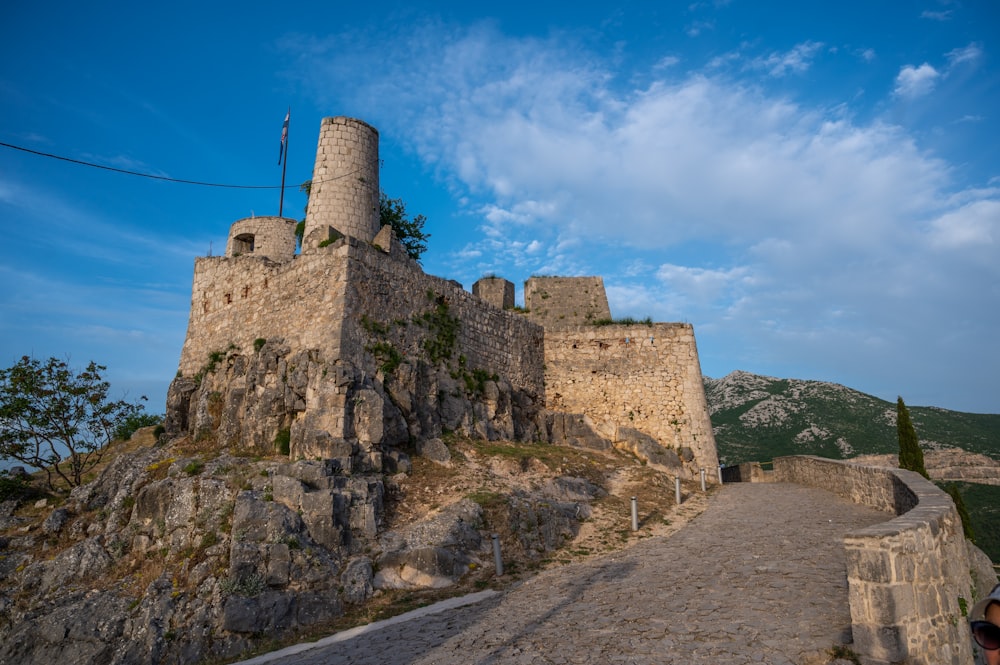 a stone castle on a hill with a blue sky in the background