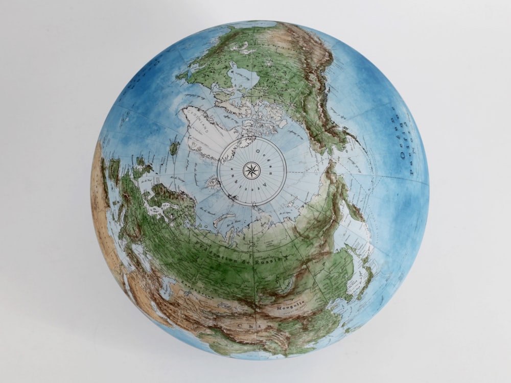 a blue and green globe sitting on top of a white table