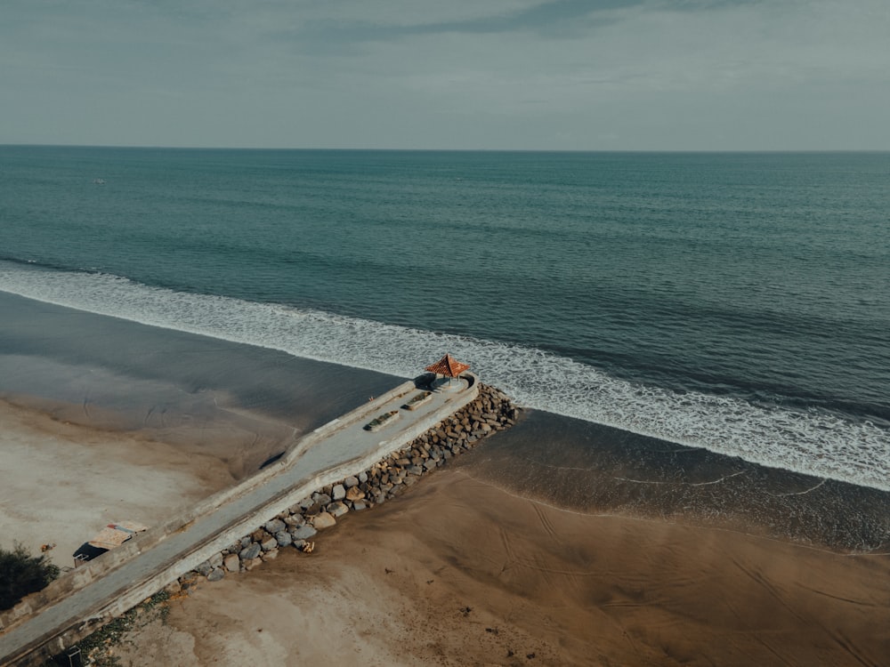 an aerial view of a man sitting on a wall next to the ocean