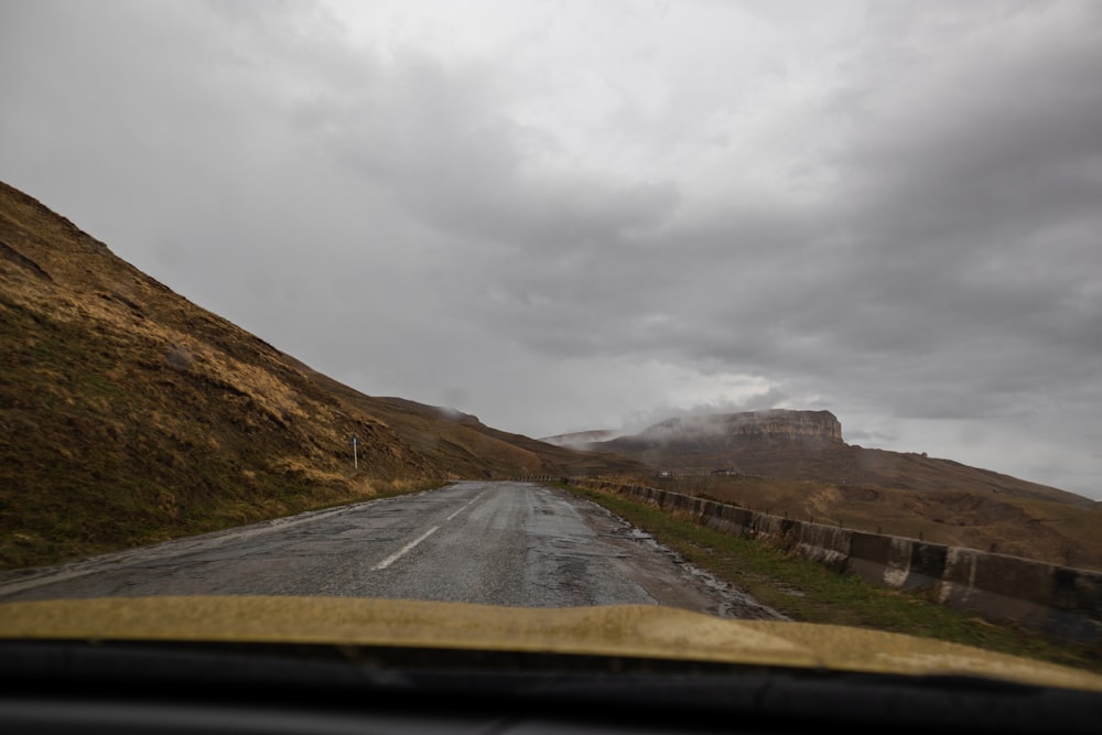 a car driving down a road with a mountain in the background