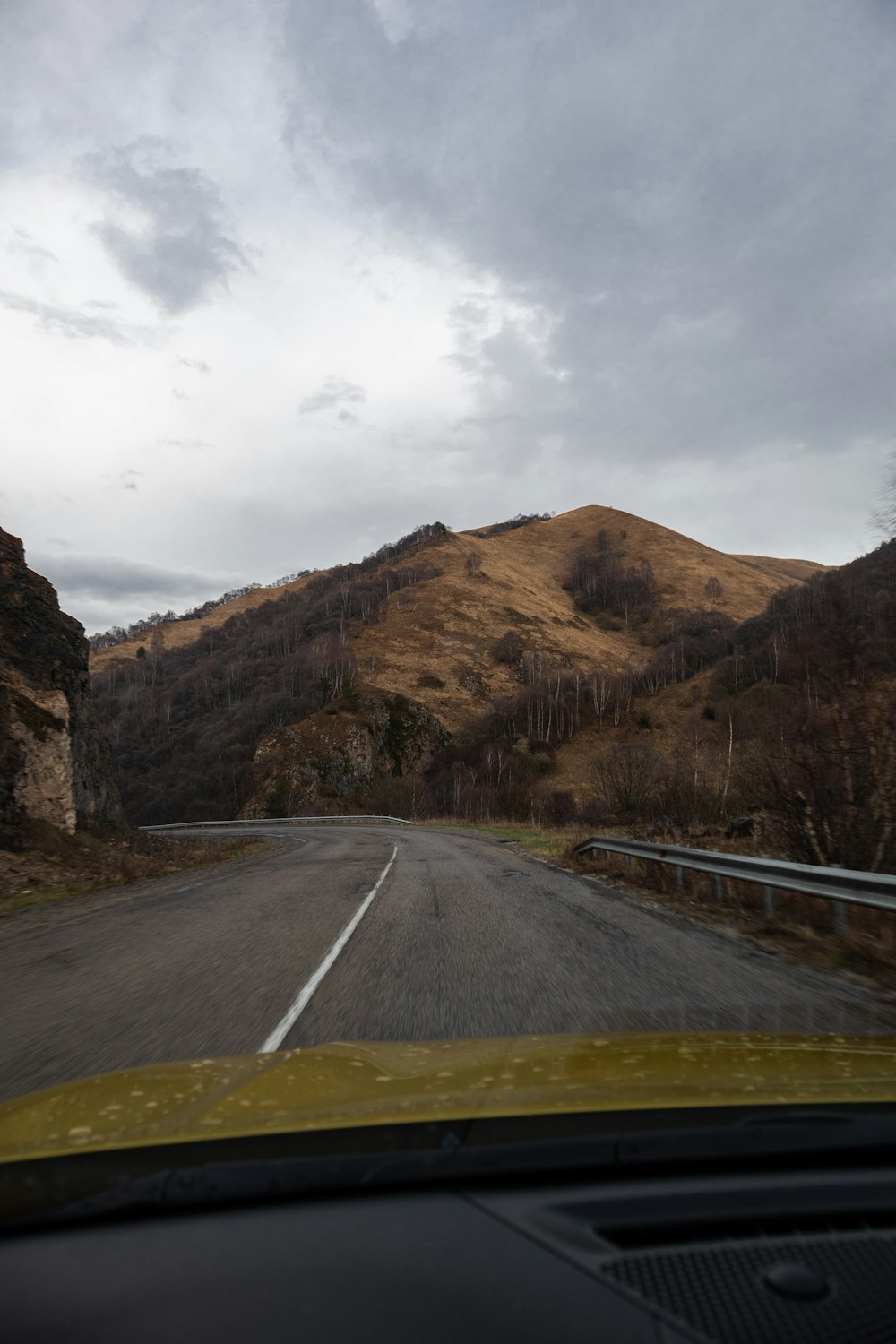 un coche conduciendo por una carretera junto a una montaña