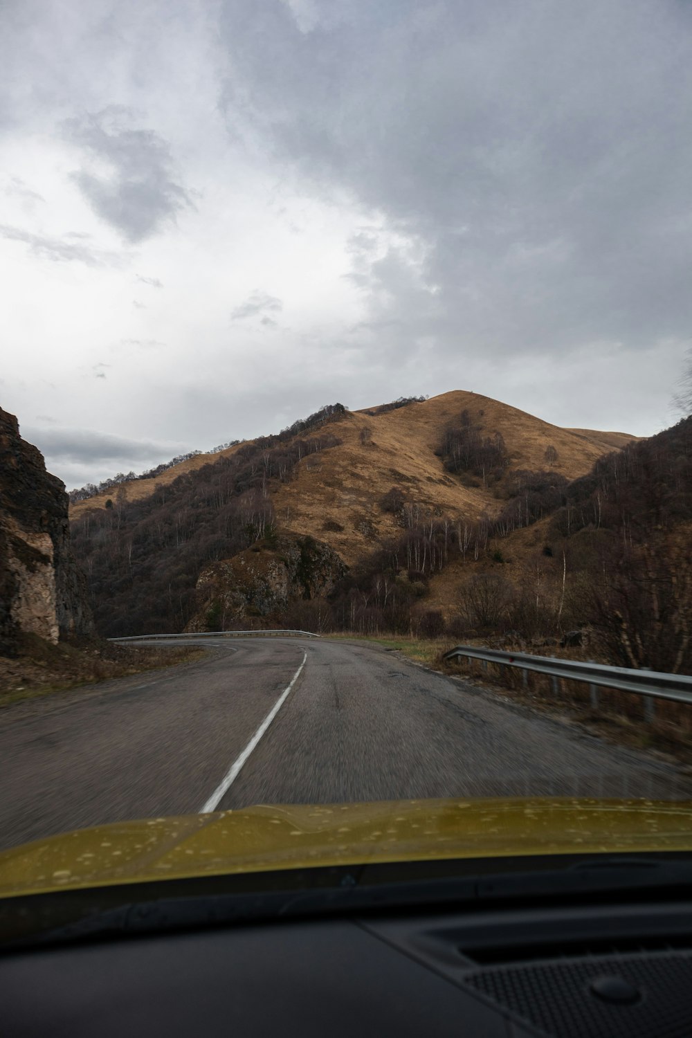 a car driving down a road next to a mountain