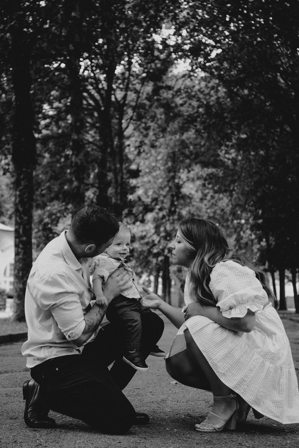 a man kneeling down next to a woman holding a baby