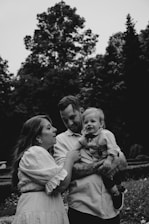 a black and white photo of a man and woman holding a baby