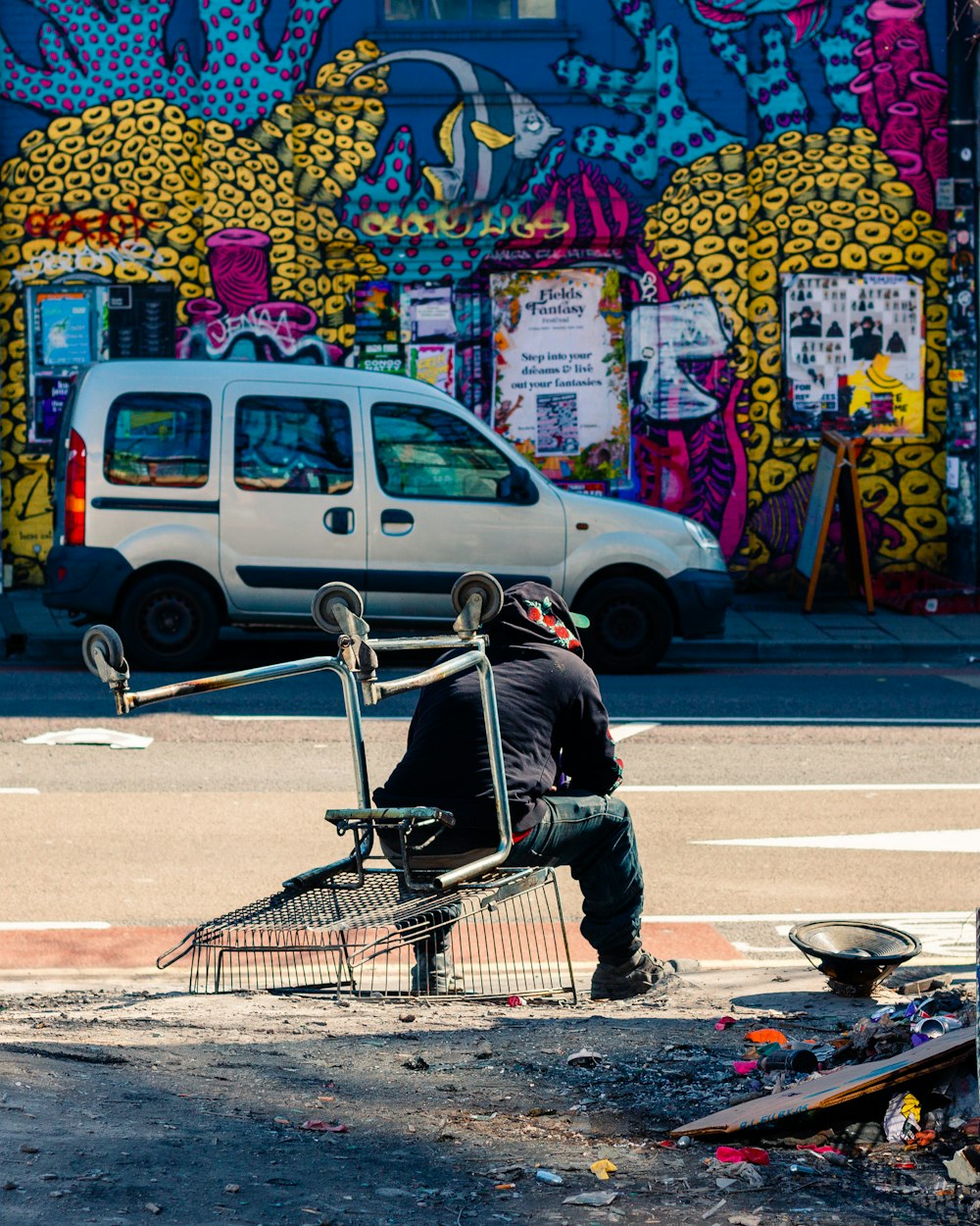 a man sitting in a shopping cart on the side of a road