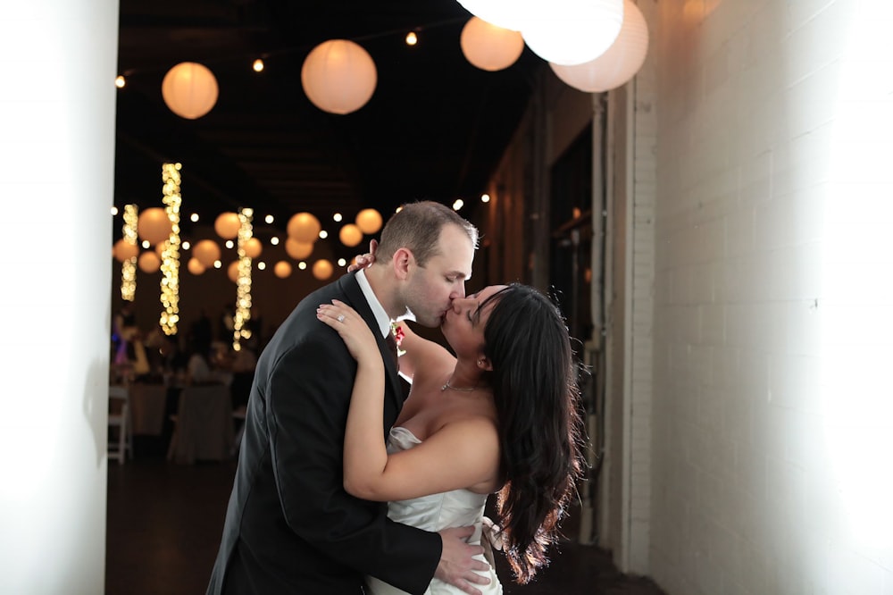 a bride and groom kissing in a hallway