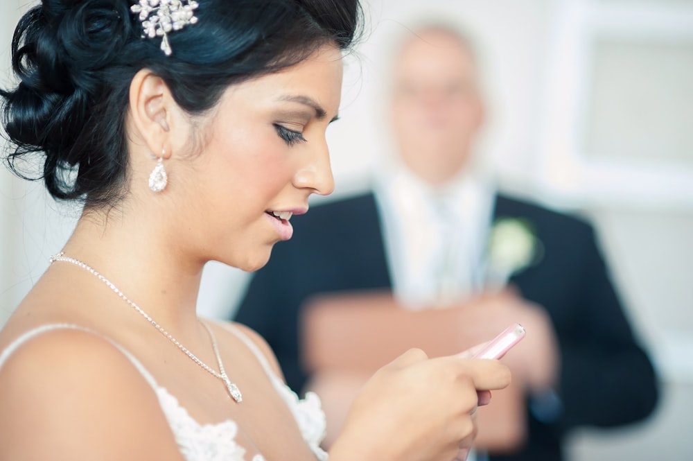 a woman in a wedding dress looking at her cell phone