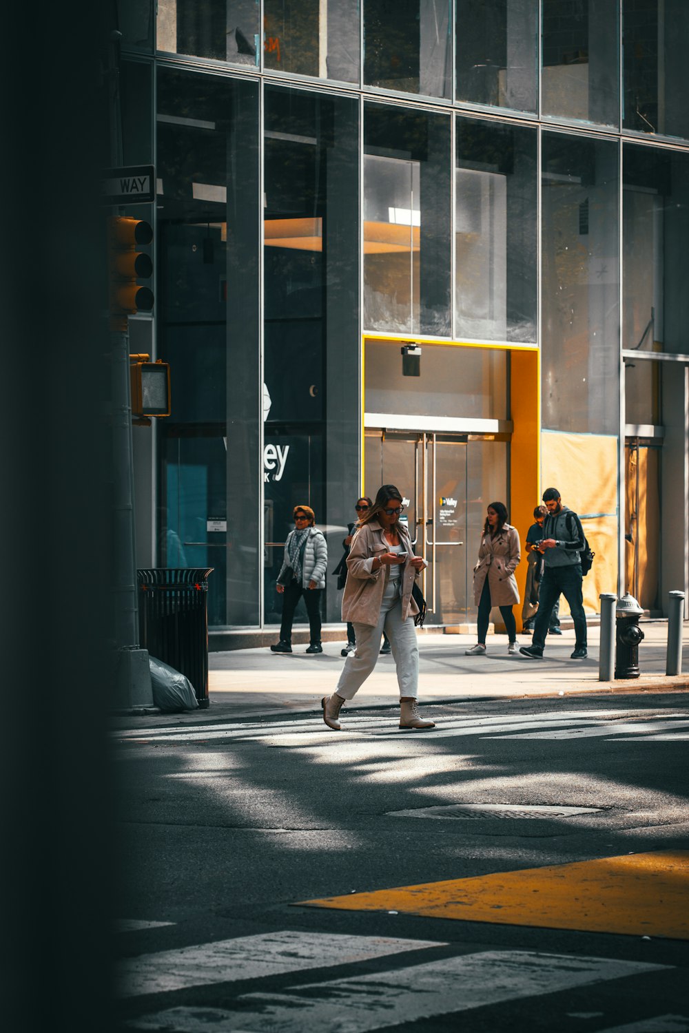 a group of people walking across a street next to a tall building