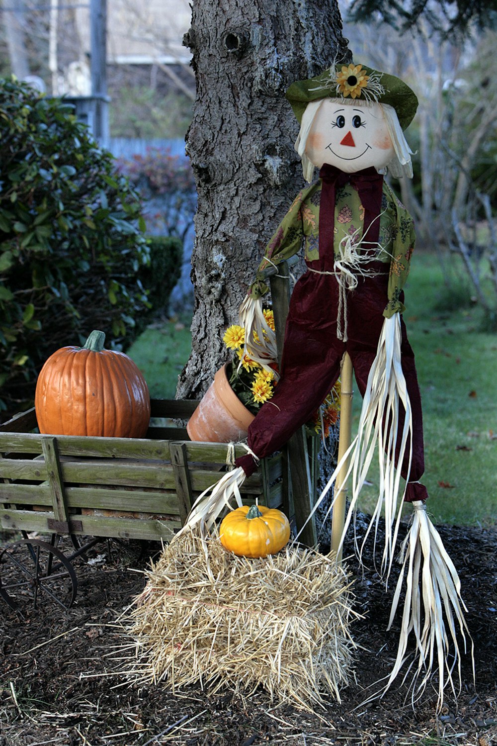 a scarecrow sitting on a bench next to a tree