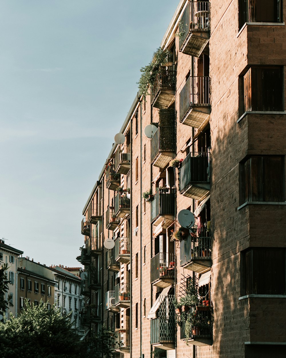 a tall brick building with balconies and plants on the balconies