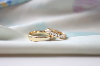 two wedding rings sitting on top of a white cloth