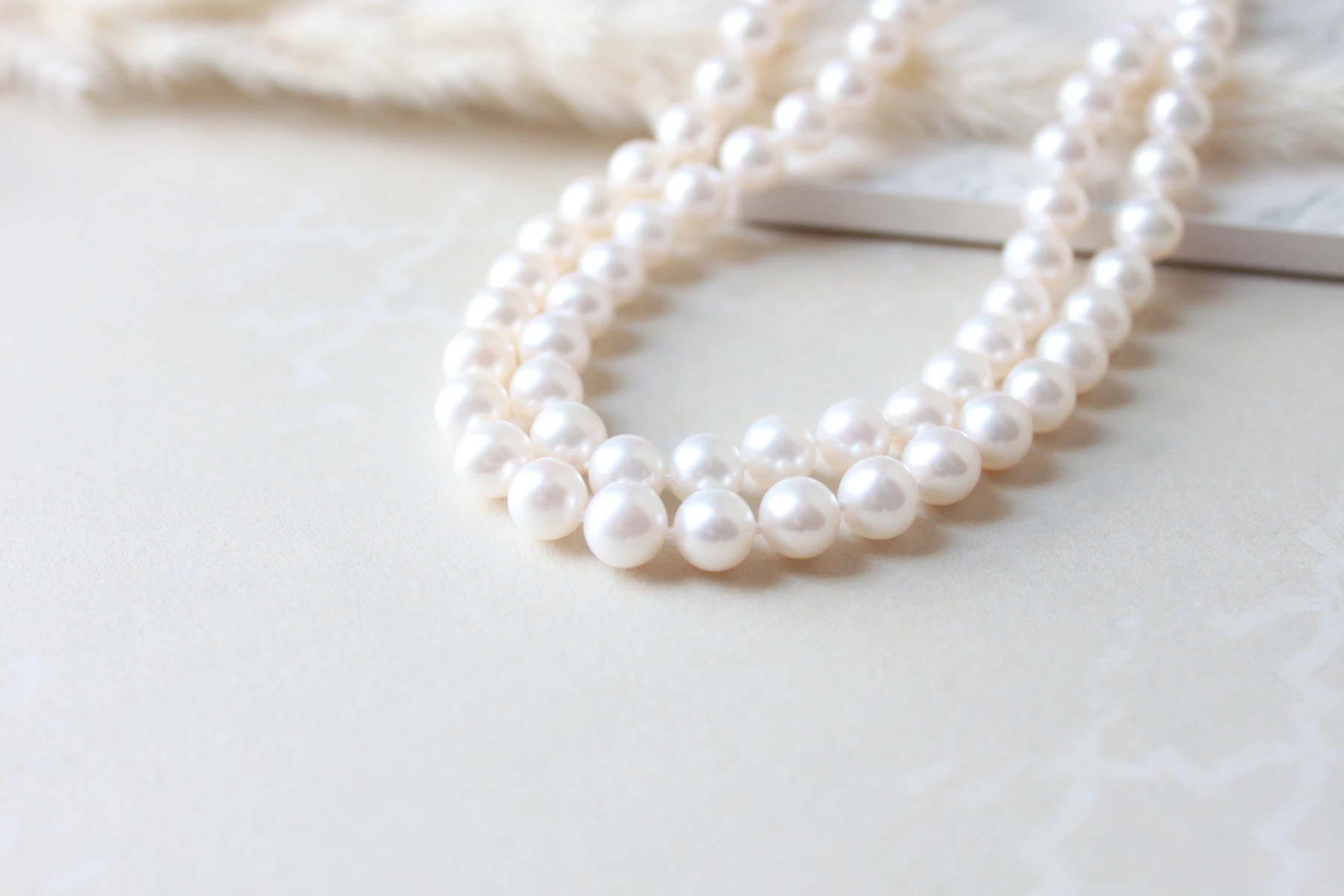 White pearl strands arranged on a pale surface, with lustre and matching visible in close detail