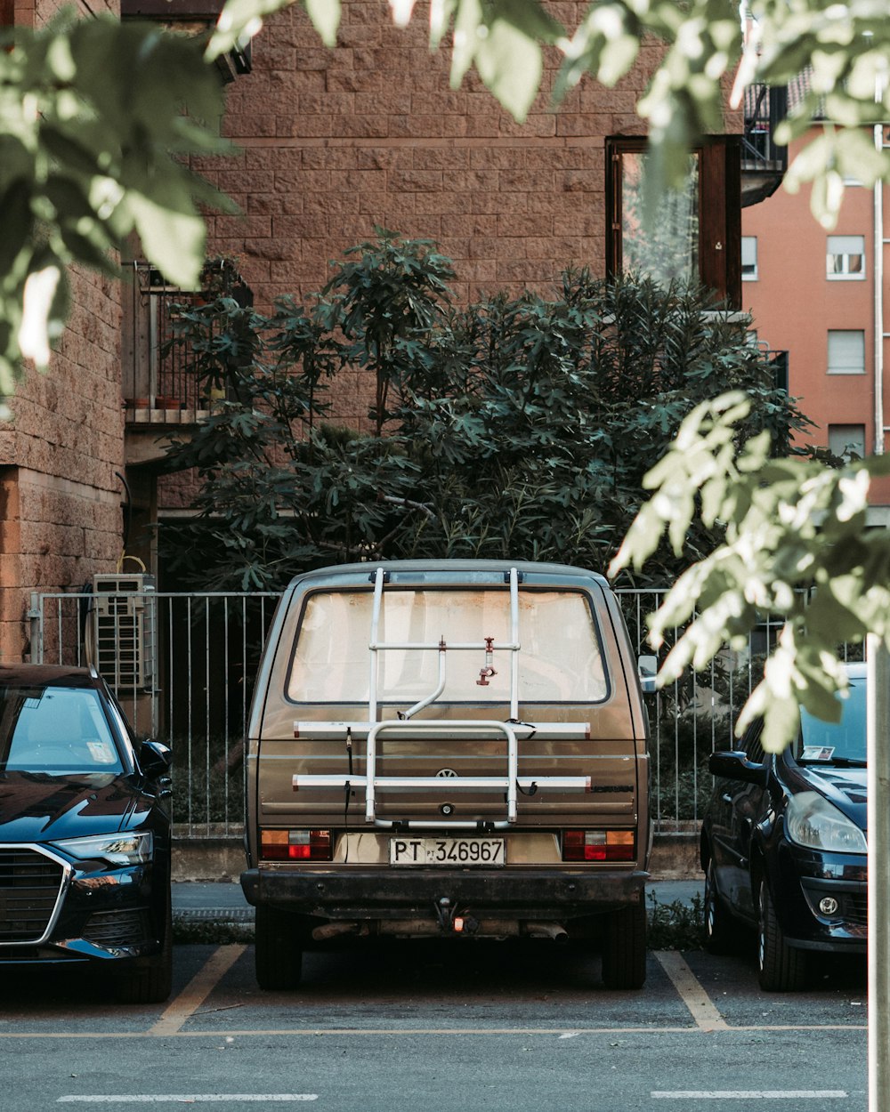 a brown van parked in a parking lot next to a black car