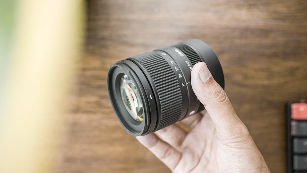 a person holding a camera lens in their hand