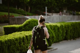 A person listening to a podcast while walking in a park, earbuds in and phone in hand.