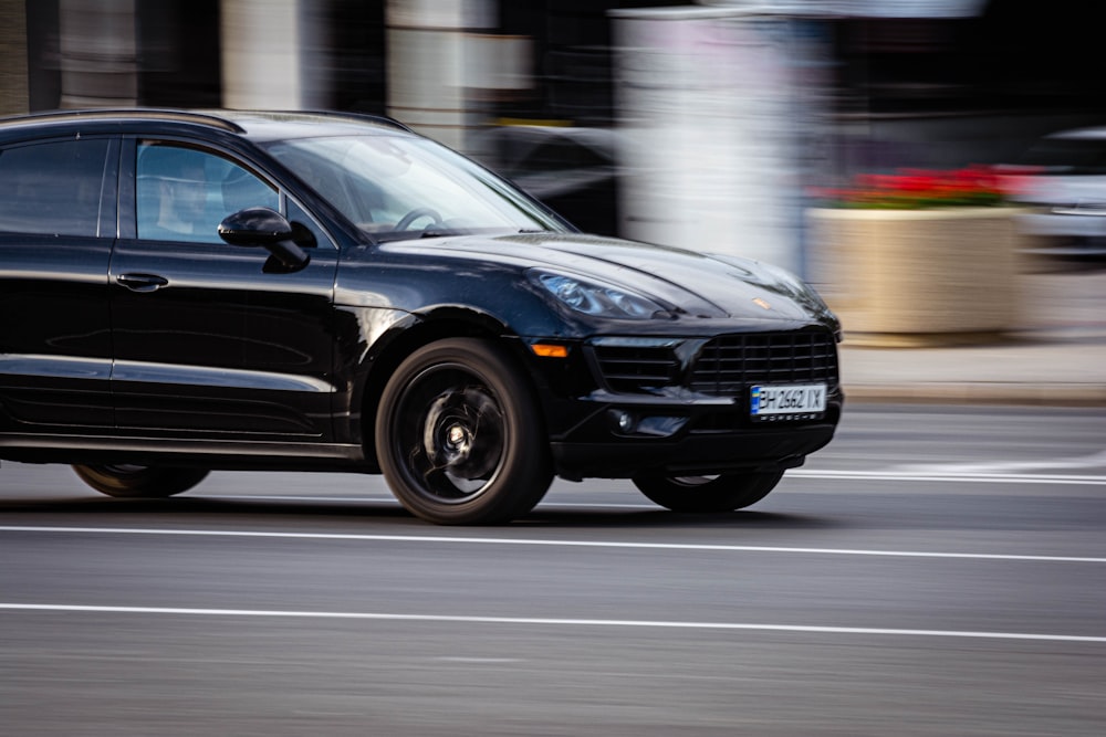 a black porsche cayen driving down a street