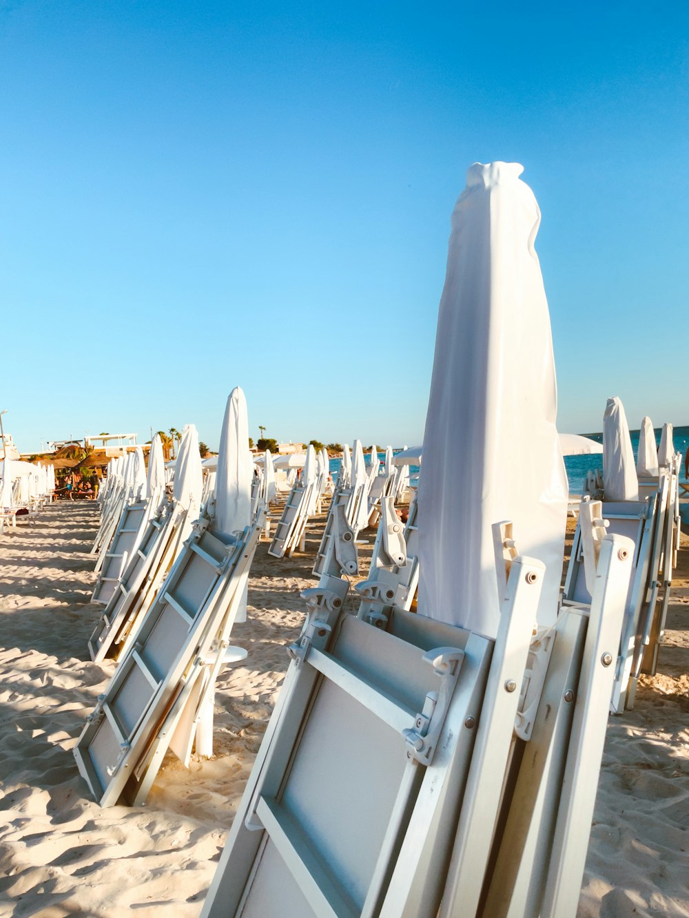 a row of white beach chairs sitting on top of a sandy beach