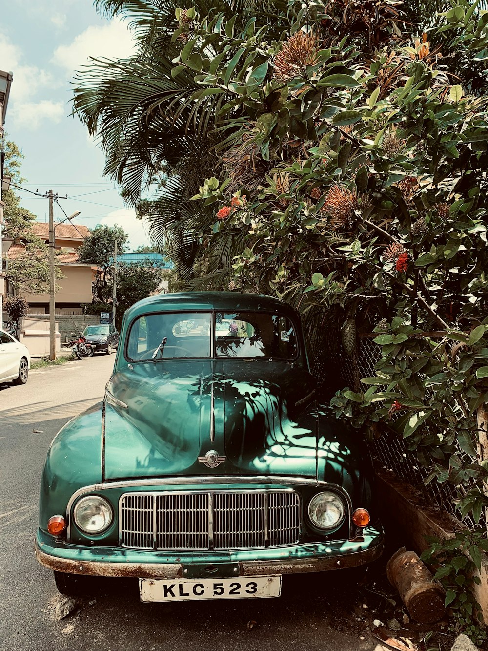 an old green car parked on the side of the road