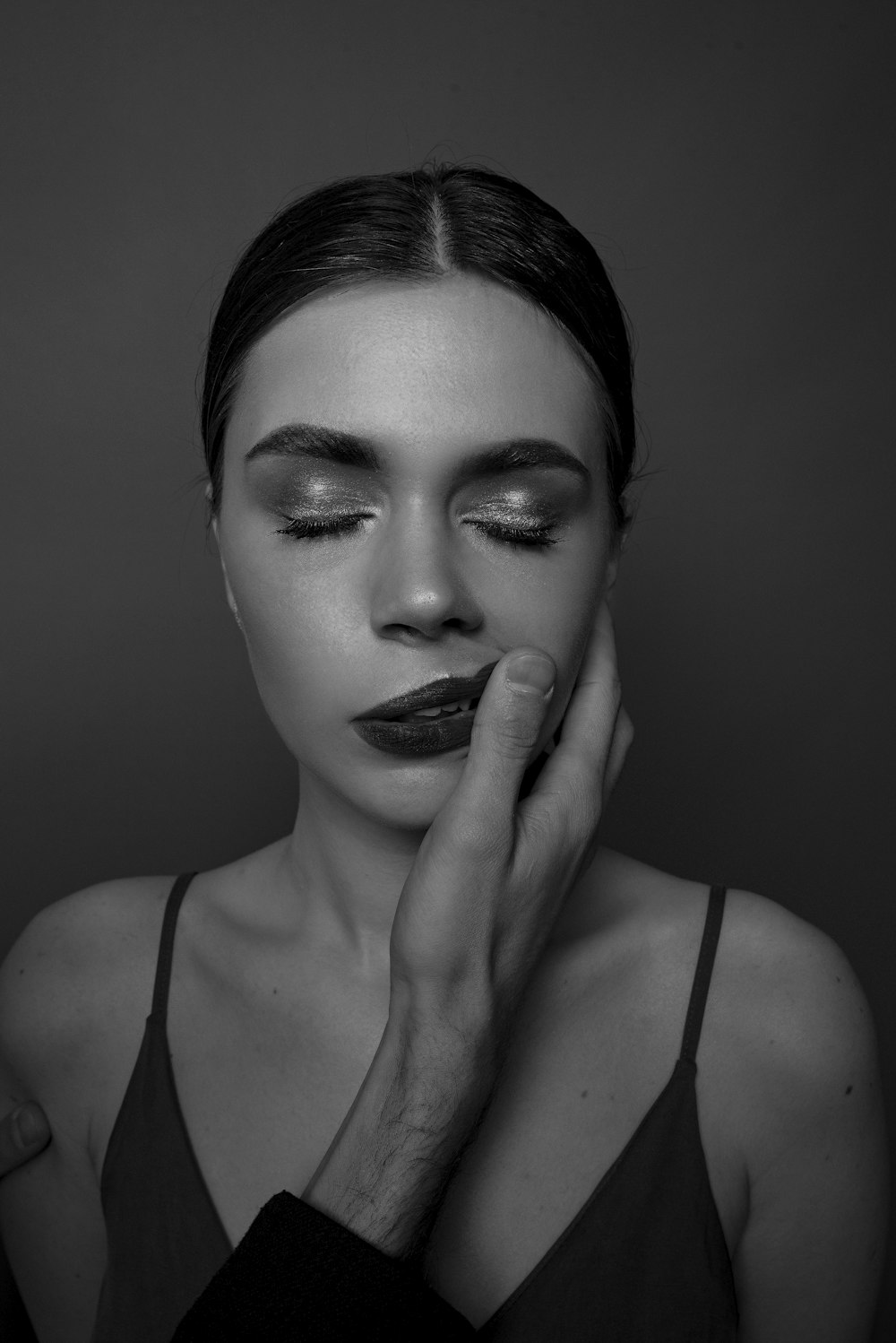 a black and white photo of a woman with her hands on her face