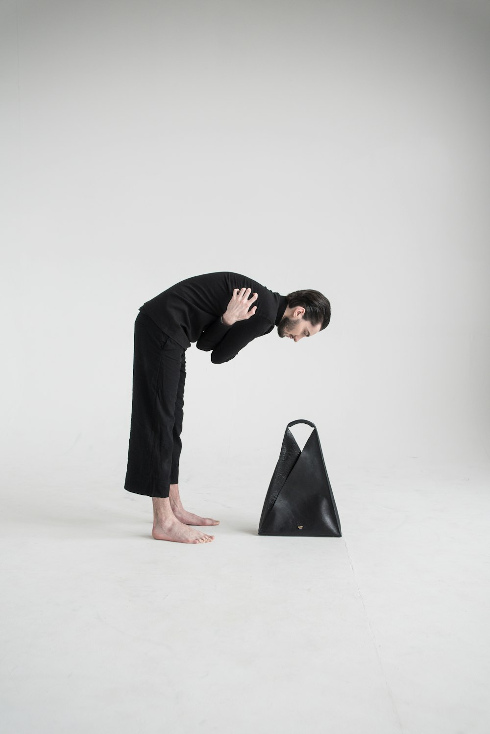 a woman bending over a black bag on a white background