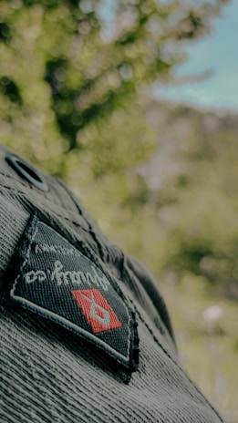 Close-up of a bmck member's leather jacket patch featuring the club logo, with a blurred forest background.
