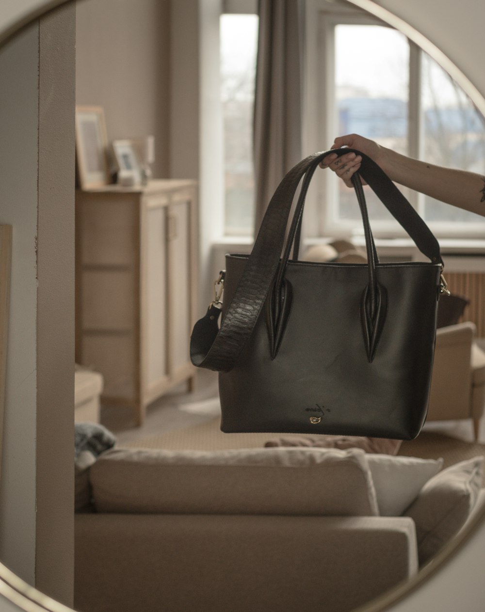 a woman holding a black purse in front of a mirror