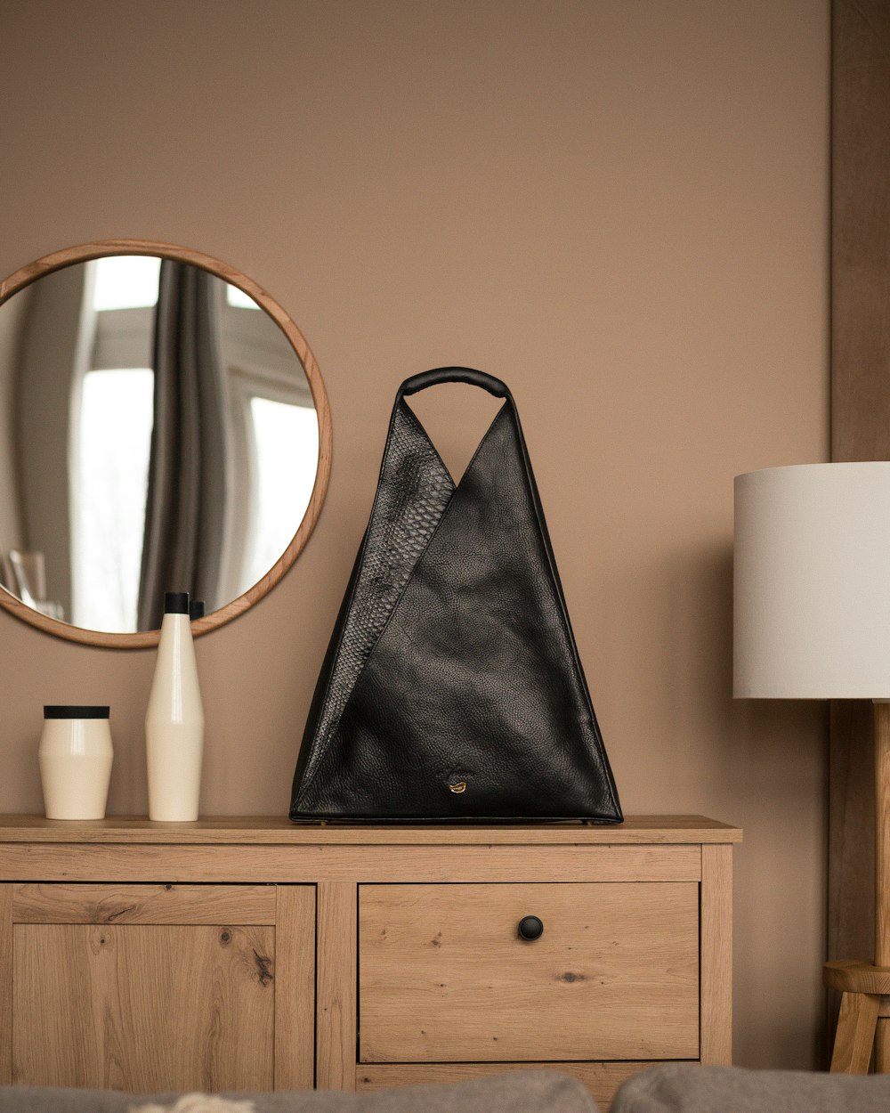 a black purse sitting on top of a wooden dresser