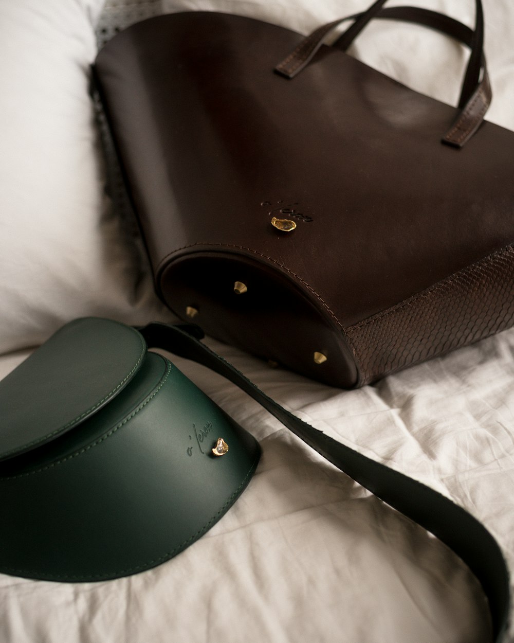 a brown and green purse sitting on top of a bed