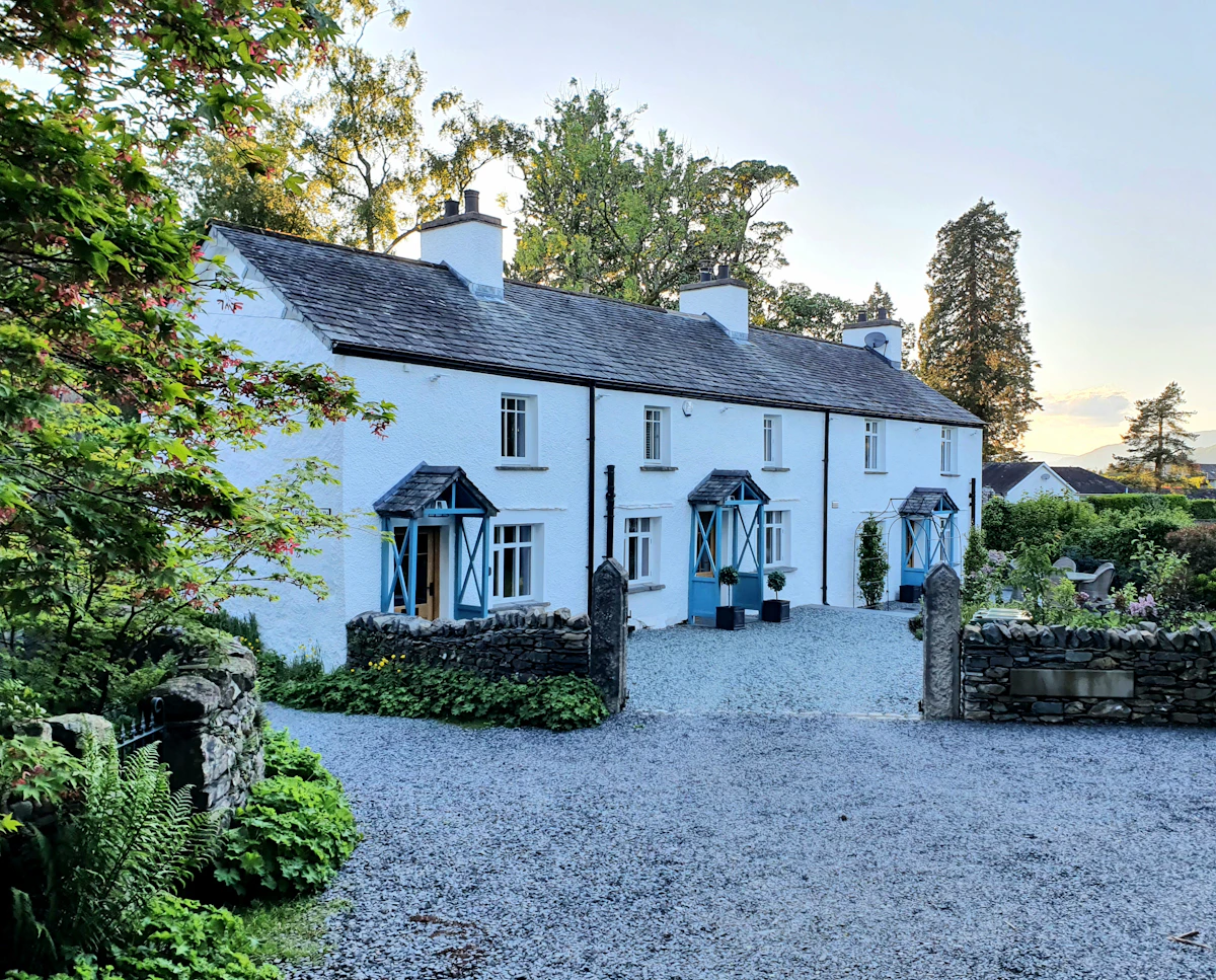 A white period cottage photographed in warm evening light, presented for sale