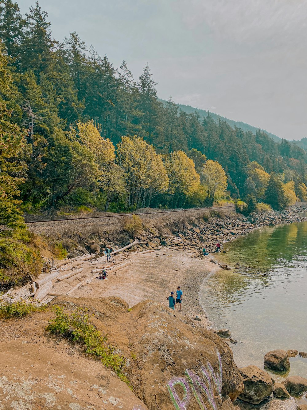 a group of people sitting on the shore of a lake