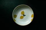 A bright yellow ceramic plate filled with fresh fruit, set on a linen cloth with soft natural light.