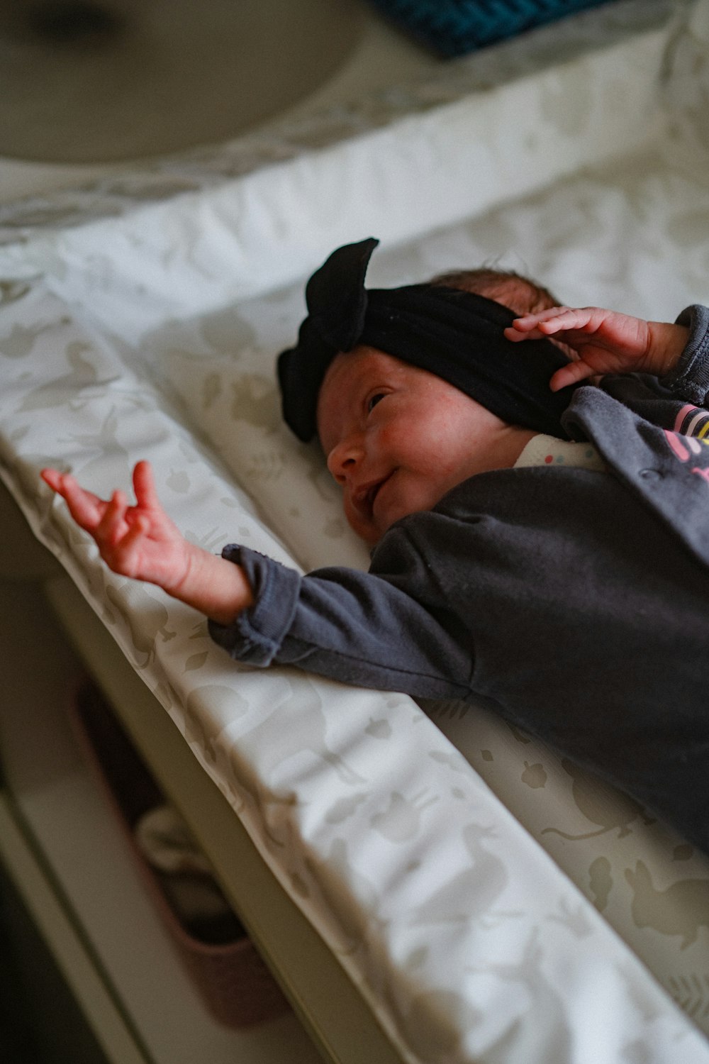 a baby laying on a bed with a black hat on