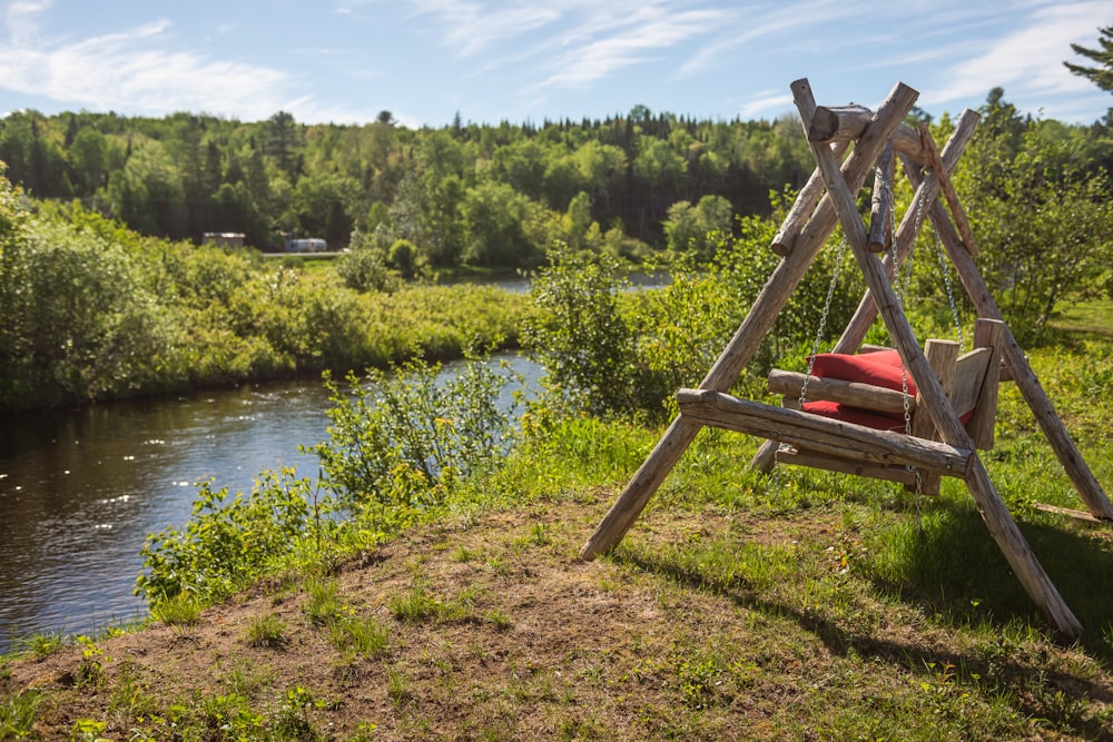 a wooden swing sitting next to a river