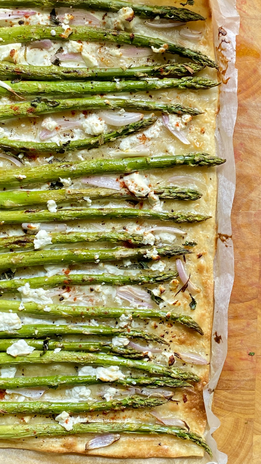 a pizza with asparagus on top of a wooden table