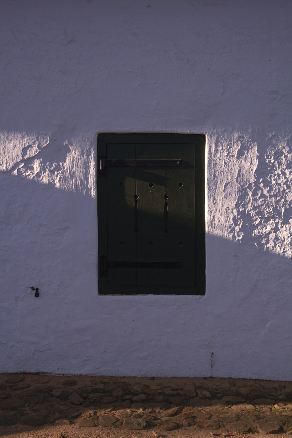 a white wall with a window and a black door