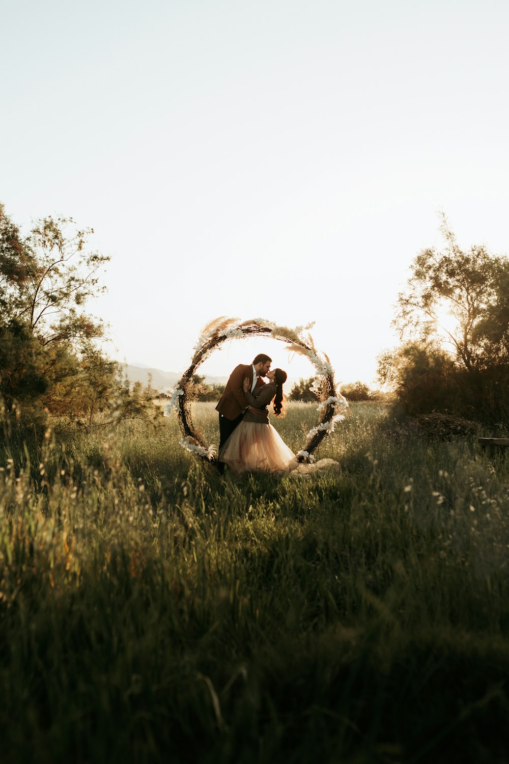 a bride and groom standing in a field