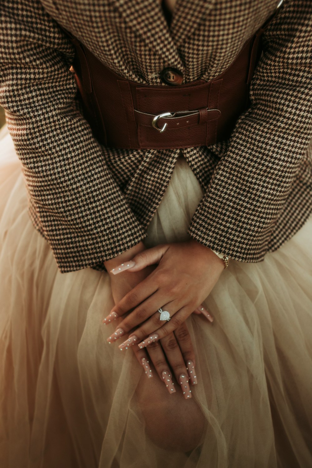 a woman in a dress and jacket holding her hands together