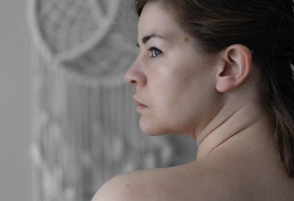 a close up of a woman's neck with a dream catcher in the background