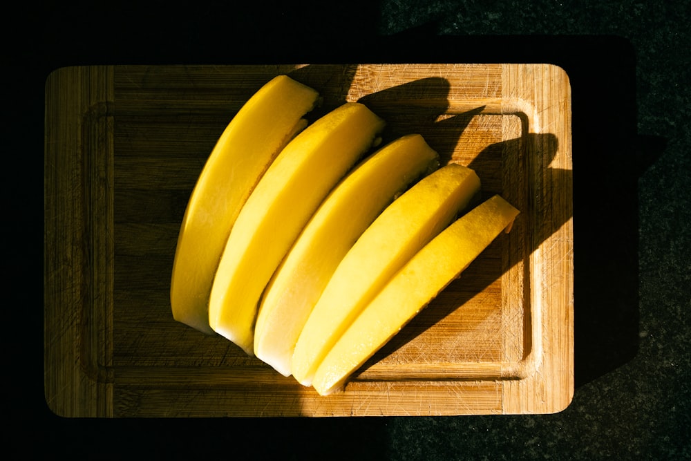 a wooden cutting board topped with sliced bananas