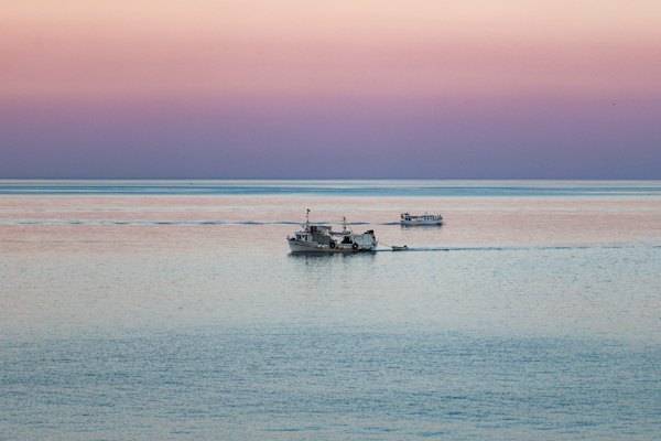A couple of boats floating on top of a large body of water — Skiathos, Greece