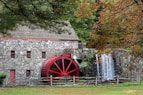 a red water wheel in front of a stone building