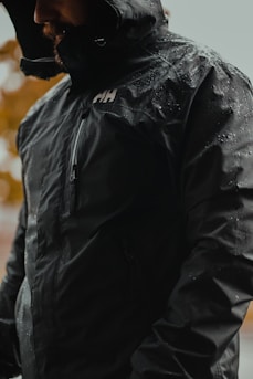 a man wearing a black jacket and a black hat