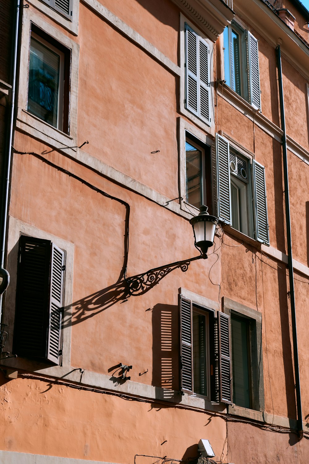 a building with shutters and a clock on the side of it