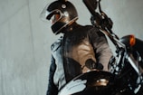 a man in a leather jacket and helmet standing next to a motorcycle